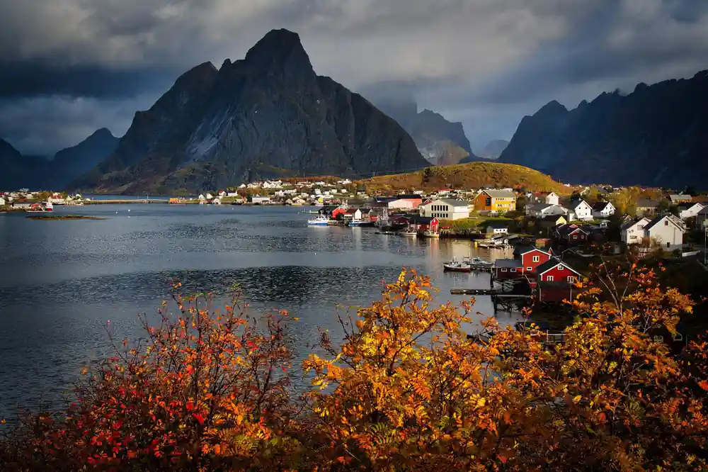 Coastal village with red boathouses and autumn vegetation