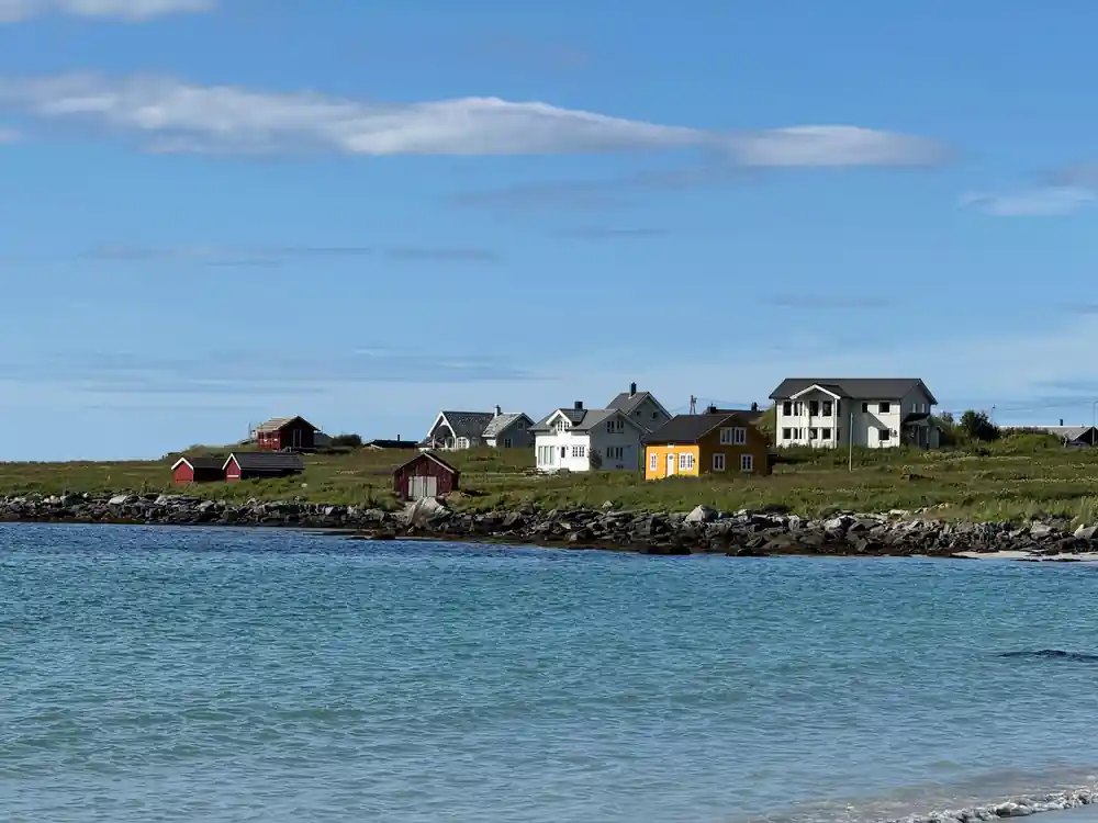 Colorful houses on rocky shore with turquoise water and mountains