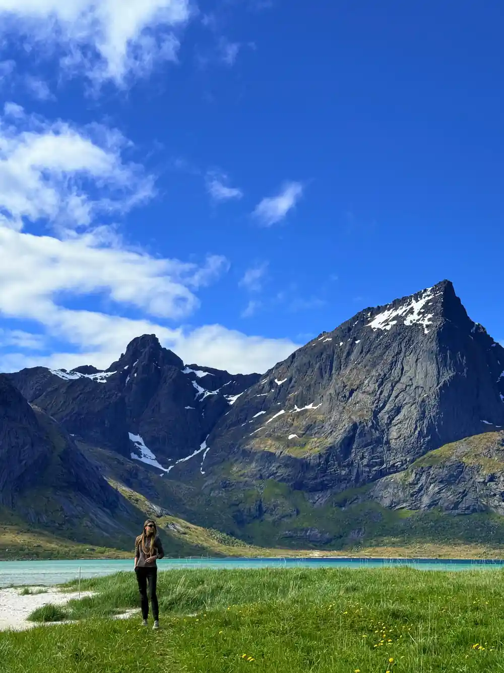 Hiker standing by turquoise alpine lake and peaks