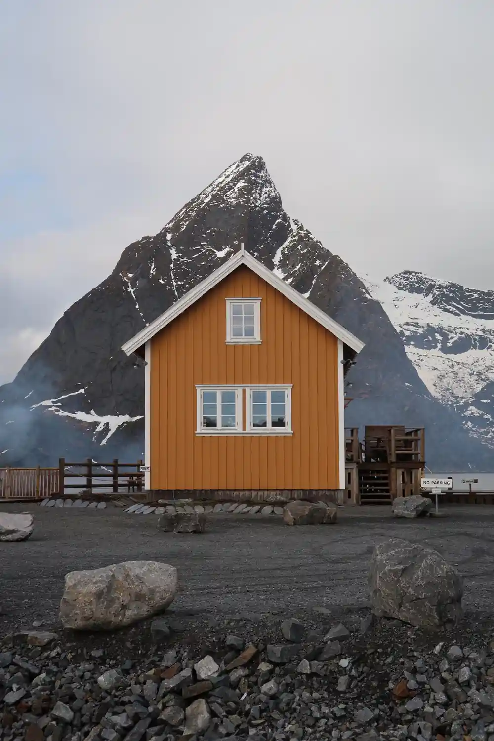 Orange cabin with three windows below dramatic snow-covered mountain