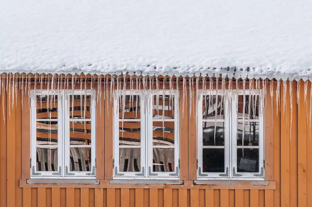 Orange wooden building with white-framed windows covered in snow