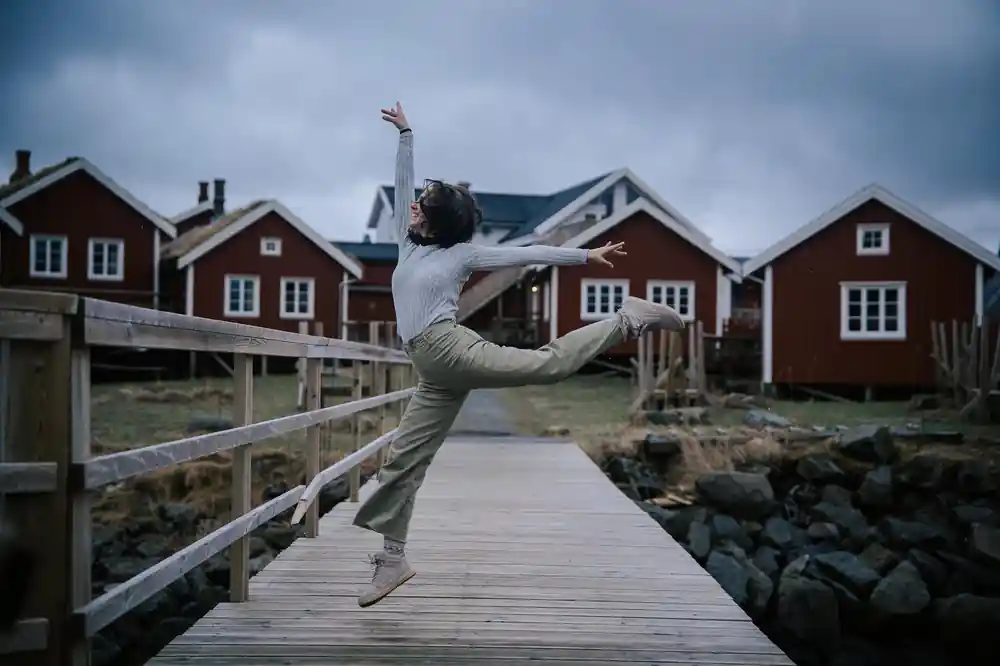 Person jumping on wooden boardwalk near red houses