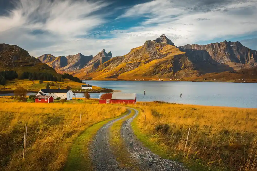 Red houses beside mountain lake with grassy valley and mountains
