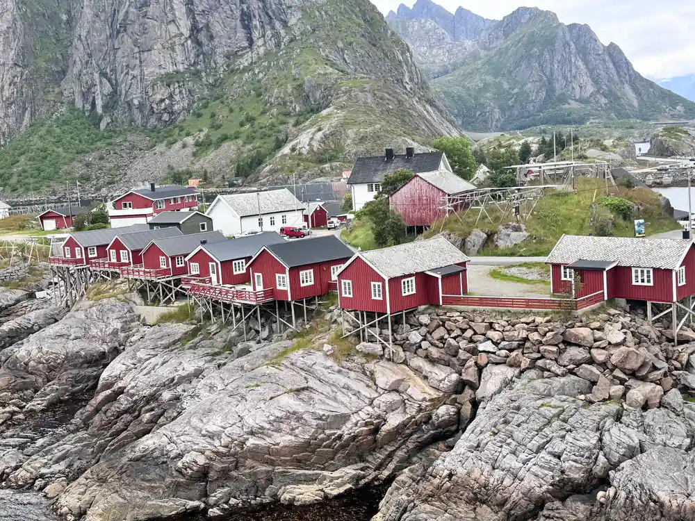 Red wooden cabins on rocky outcrop beneath steep peaks