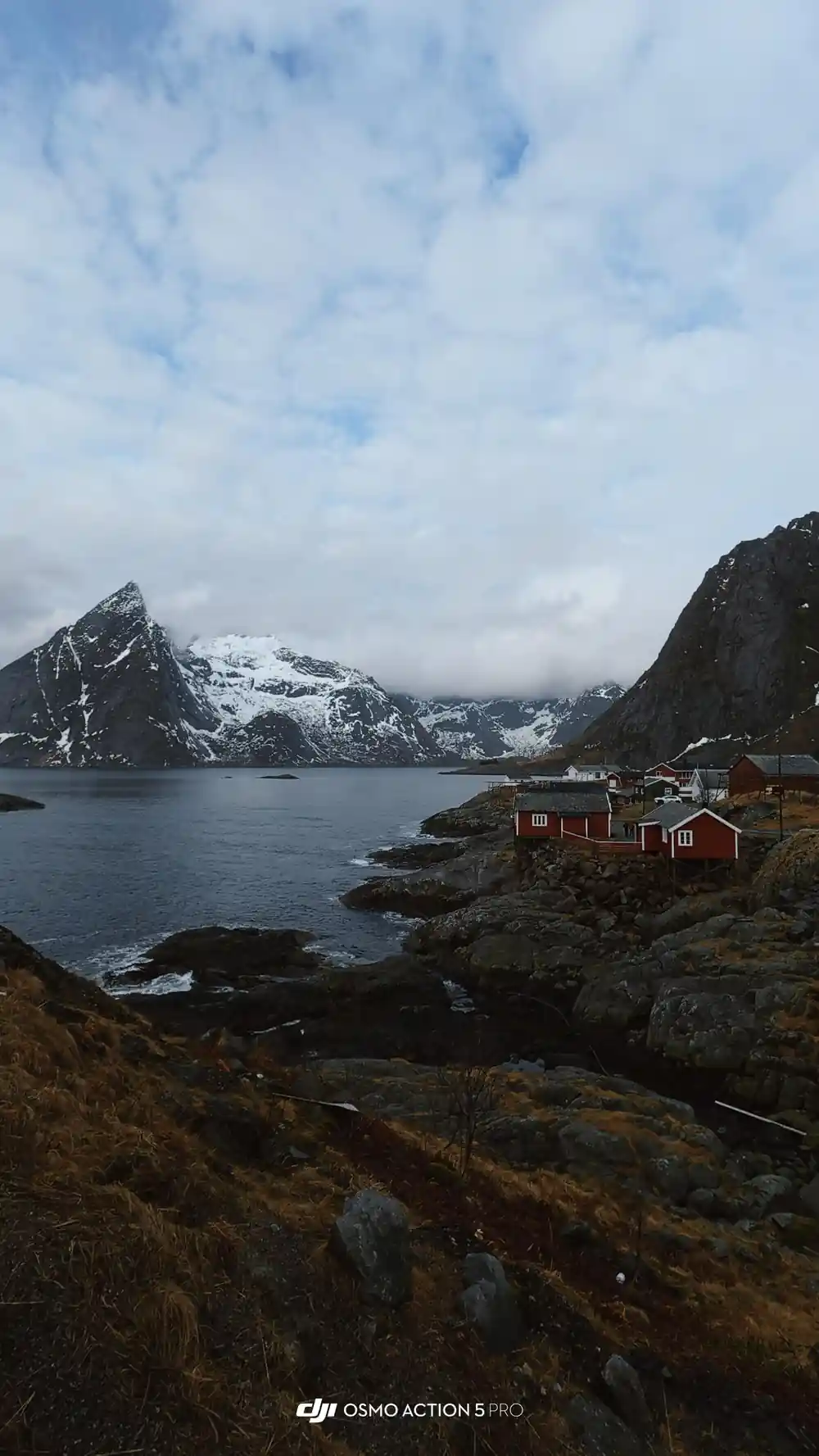 Rocky coastline with red buildings nestled below steep mountains