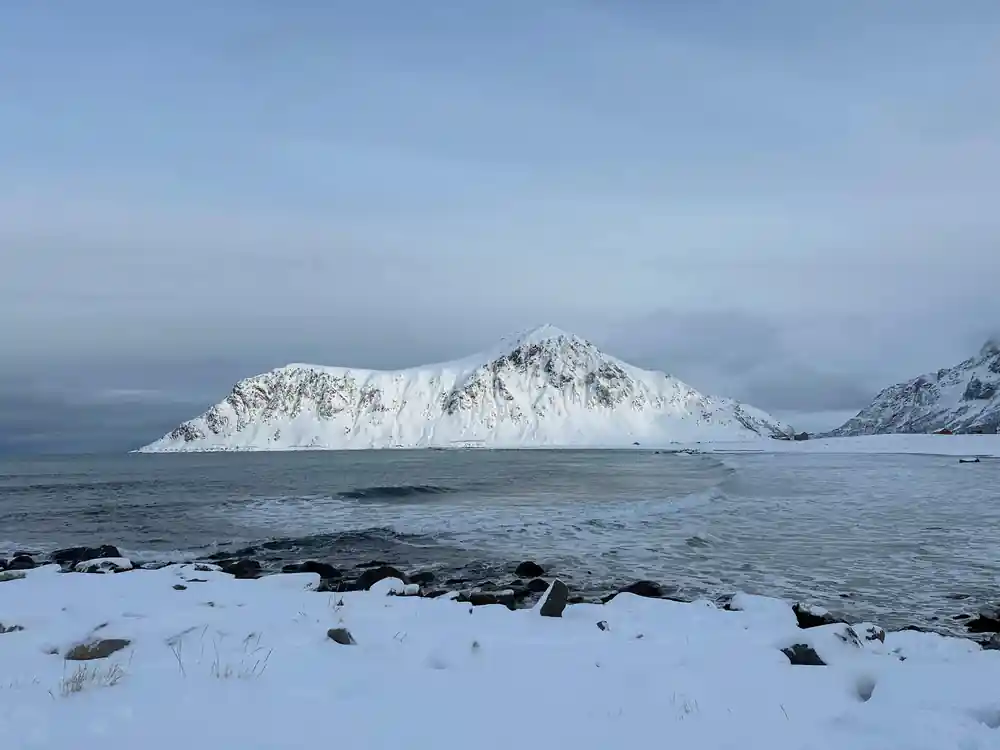 Snow-covered island mountain across grey water