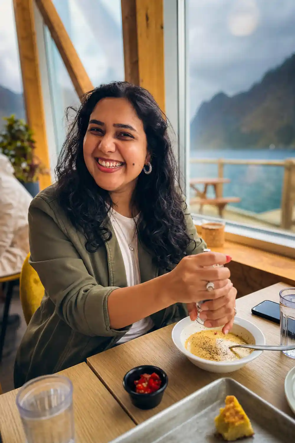 Woman smiling at table with food and mountain view window