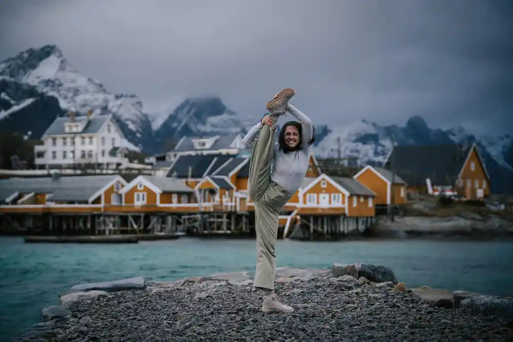 Woman stretching on beach with yellow waterfront houses and mountains